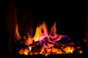 Bright fire burns on coals close-up. Carbon dioxide flies out with a blue spark.