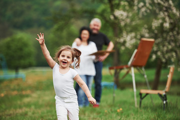 Running forward. Grandmother and grandfather have fun outdoors with granddaughter. Painting conception