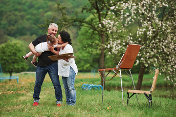 Calm and quiet atmosphere. Grandmother and grandfather have fun outdoors with granddaughter. Painting conception