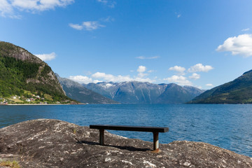 Fjord in Norway on a sunny day. Beautiful Norwegian landscape. Bench on the fjord bank.