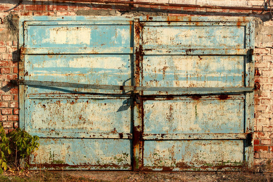 Old metal garage doors. Flaking paint and rust on gates of abandoned building.