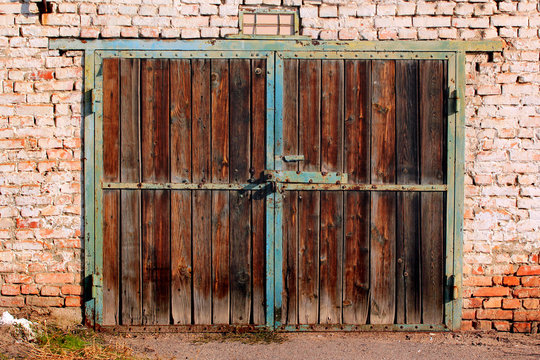 Old wooden garage doors. Flaking paint and rust on gates of abandoned building.