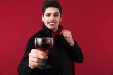 Image of vampire man with fangs in halloween costume drinking blood