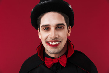 Image of handsome vampire man with fangs in halloween costume smiling
