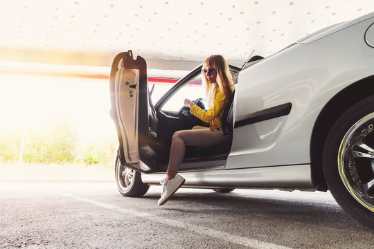 Business Lady Gets Out Of The Car In The Underground Garage. To Get Rich. Beautiful Successful Gorgeous Girl Sitting In The Convertible Cabrio Car On The Warm Sunny Day In A City.