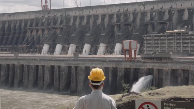 Engineer wearing a safety helmet, supervising the biggest world's dam, Itaipu dam between the border of Paraguay and Brazil. 4k