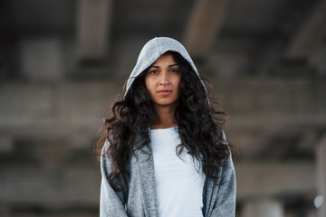 Portrait of beautiful young woman standing under the bridge outdoors