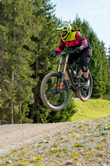 Fototapeta na wymiar downhill mountain biker jumping high and riding hard in Lenzerheide in the Swiss Alps