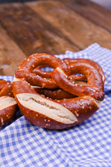 Bavarian pretzel decorated with a blue and white cloth on a rustic wooden board - Munich Oktoberfest. Background and free space for text. Traditional pastries for the festival. Close-up.