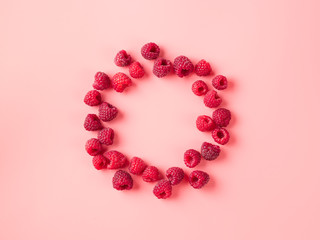 Creative layout with fresh ripe berries. Raspberry on pink background with round empty circle in center for copy space. Can use for your design. Top view or flat lay. Negative space for text