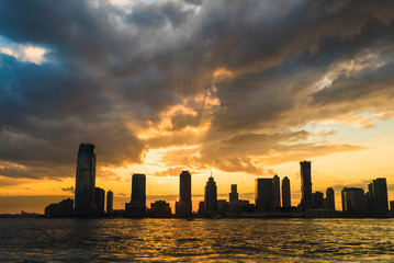 Beautiful orange sunset on the sea, silhouette of city and business and residential buildings. Sunset over city scape.