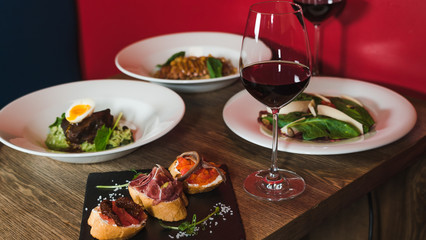 Close-up salad with grilled beef meat and boiled egg, bread with hummus and jamon near. Dinner at restaurant.