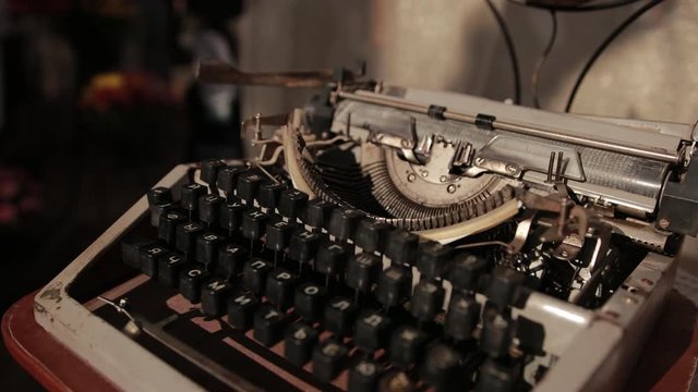 an old typewriter, which stands on table with white knitted tablecloth, close-up, slow motion