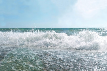 Sea wave on a stone beach on a sunny summer day