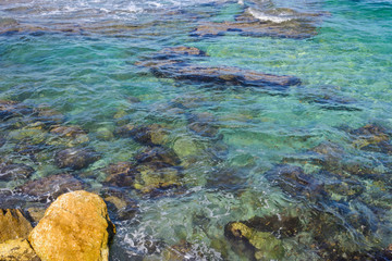 sea foam near the rocky shore. clear turquoise water