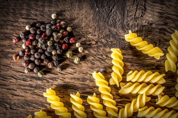 Background Italian spiral paste, bay leaves, spices and multicolored round peppers lie on a...