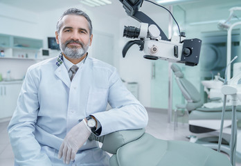 Bearded dentist posing in private modern clinic.