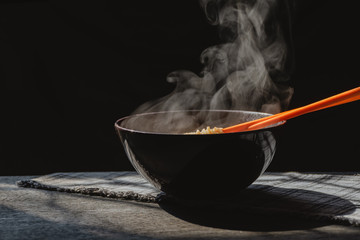 Steam and smoke Instant noodles in bowl on wooden table and nature light and black background,...
