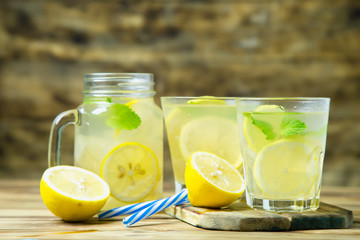 Lemonade or mojito cocktail with lemon and mint on wood background