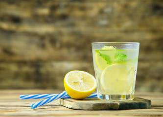 Lemonade or mojito cocktail with lemon and mint on wood background