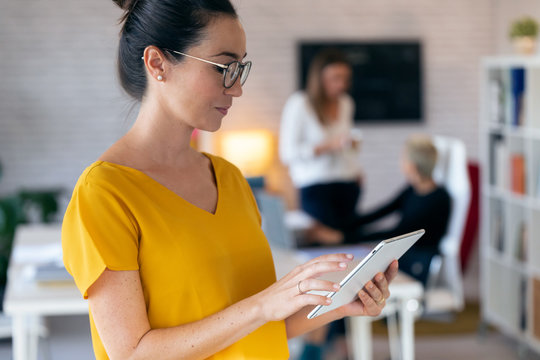 Concentrated Young Entrepreneur Woman Using Her Digital Tablet While Standing In The Office.