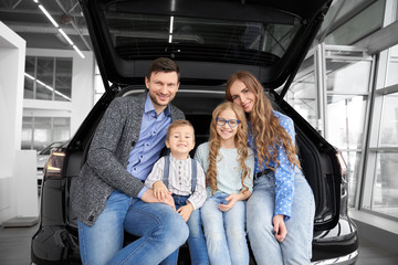 Sweet family sitting together on trunk on car and posing