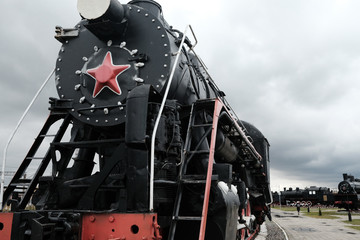 Old Russian locomotive. Steam locomotive with red wheels. Retro locomotive on rails. Black locomotive with red star.