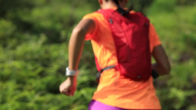 Woman ultramarathon runner  set the smartwatch running up on mountain slope in tropical rainforest,4k