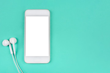 White smartphone with headphones on mint background. Flat lay. Space for your text.