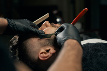 Handsome bearded man is getting shaved by hairdresser