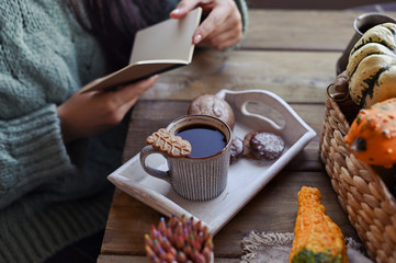 Autumn concept, pumpkins, hot steaming cup of coffee on a wooden table background. Seasonal, morning coffee with biscuit cinnamon cookies, Sunday relaxing. Girl in a frame with a notebook.