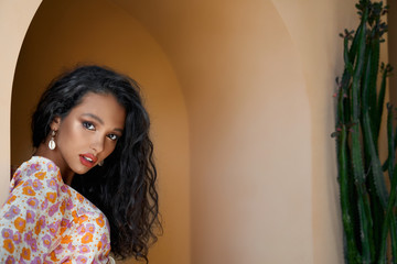 Close up of gorgeous girl in colored blouse leaning on wall