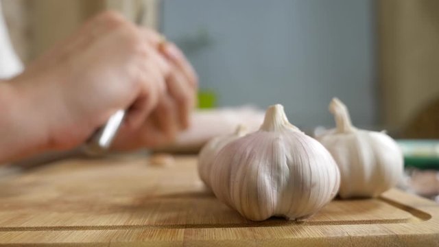 closeup head of garlic, male hands peel the garlic on a wooden board
