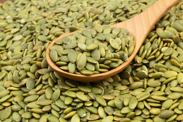 Green pumpkin seeds and wooden spoon