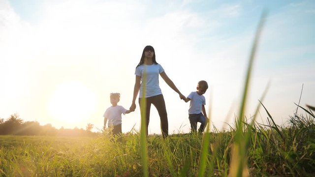 happy family funny walking go for are hold hands a teamwork Silhouette. happy little children boy and girl with mother family at sunset. mom and son mom daughter and son in white t-shirts walk on