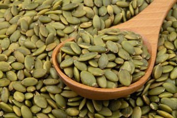 Pumpkin seeds and wooden spoon close up