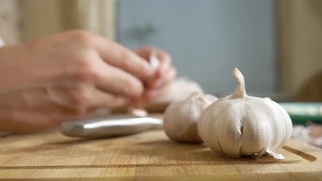 closeup head of garlic, male hands peel the garlic on a wooden board