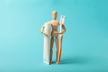 Oral hygiene and dental care. Wooden man holds toothbrush and toothpaste.