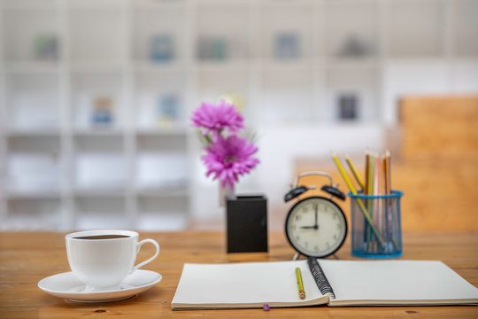 office table desk. Workspace with white  coffee cup , blank note book, colck and office supplies background.