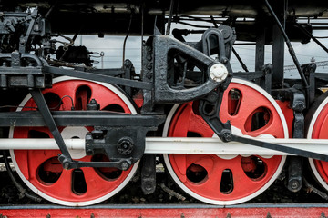 Red wheels of an old Russian locomotive on the rails close-up.
