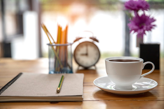 office table desk. Workspace with white  coffee cup , note book, alarm colck and office supplies background.