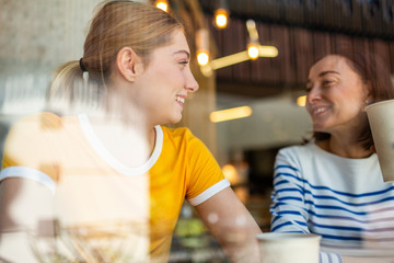 Close up mother and daughter sitting at cafe together