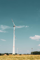 Windmills against the blue sky. Poppy and chamomile fields of Europe. The concept of eco-friendly electricity
