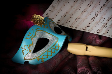 CARNIVAL MASK WITH FLUTE AND MUSIC SHEET ON BLACK BACKGROUND