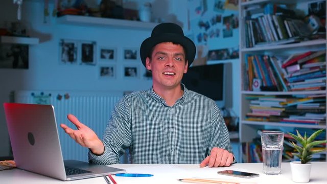 the guy at the table puts a high hat on his head