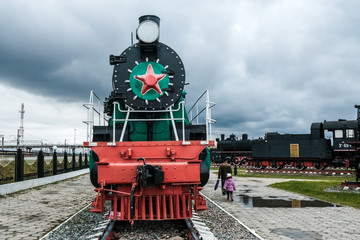 Old Russian locomotive. Steam locomotive with red wheels. Retro locomotive on rails. Black locomotive with red star.