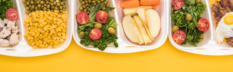 panoramic shot of eco packages with vegetables, apples, meat, fried egg and salads isolated on yellow