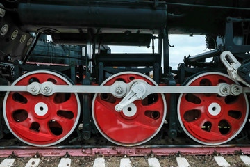 Red wheels of an old Russian locomotive on the rails close-up.