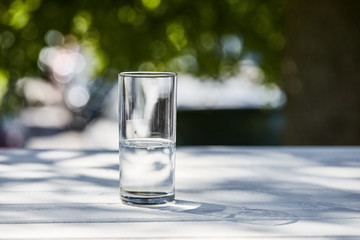 fresh clean water in transparent glass at sunny day outside on wooden table