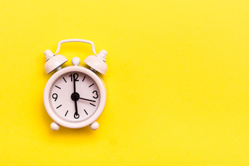 White classic alarm clock on a yellow background